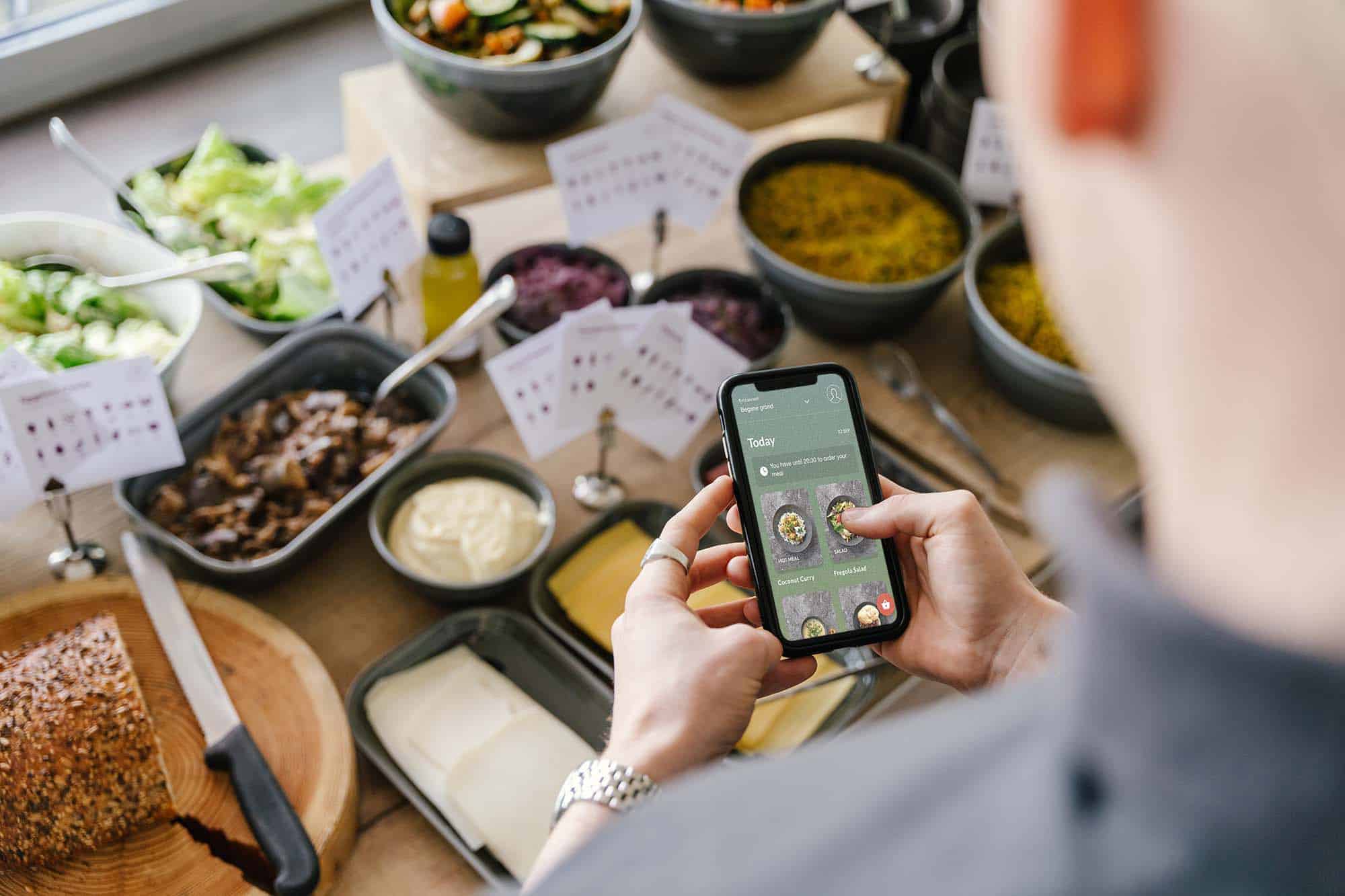 Over shoulder photo of person using the Join Program Food Feed app in company restaurant