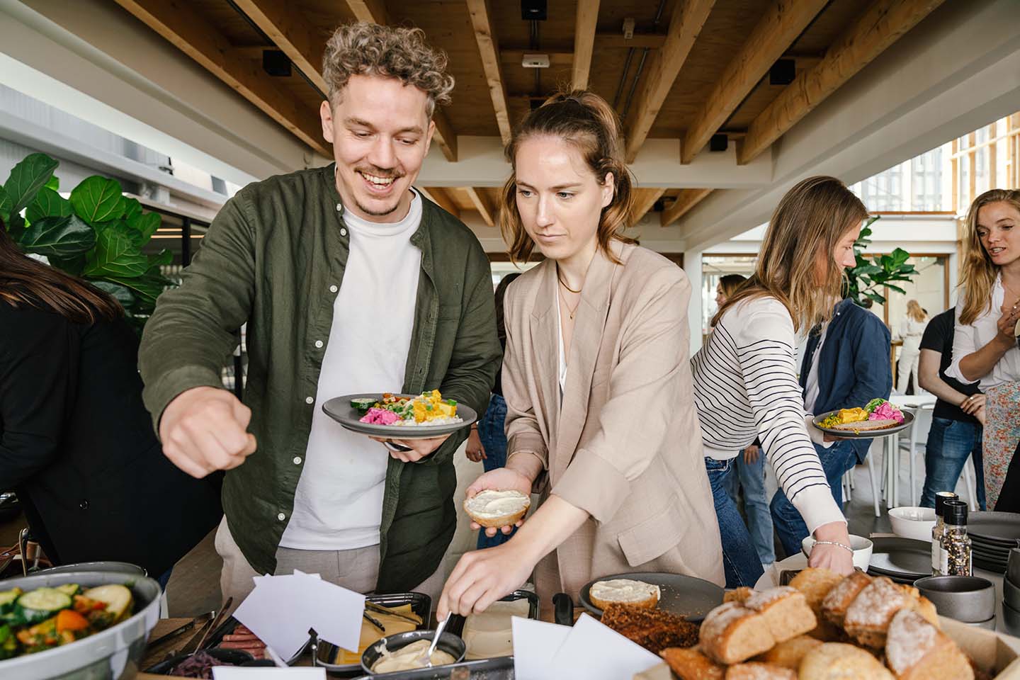 Two happy employees standing side by side selecting their lunch meals in a company restaurant